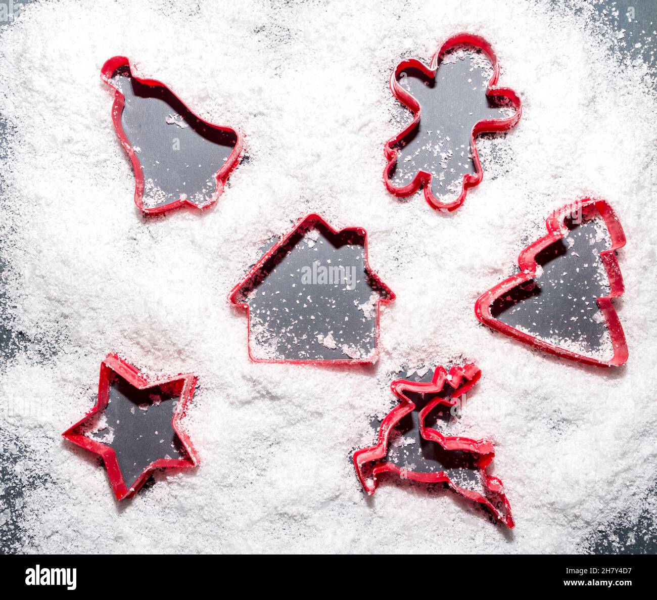 Rote Kuchenformen, die Silhouetten und Schilder im Schnee bilden. Weihnachts- und Neujahrsidee. Flach liegend, Draufsicht. Minimales abstraktes Winterurlaubs-Konzept. Stockfoto