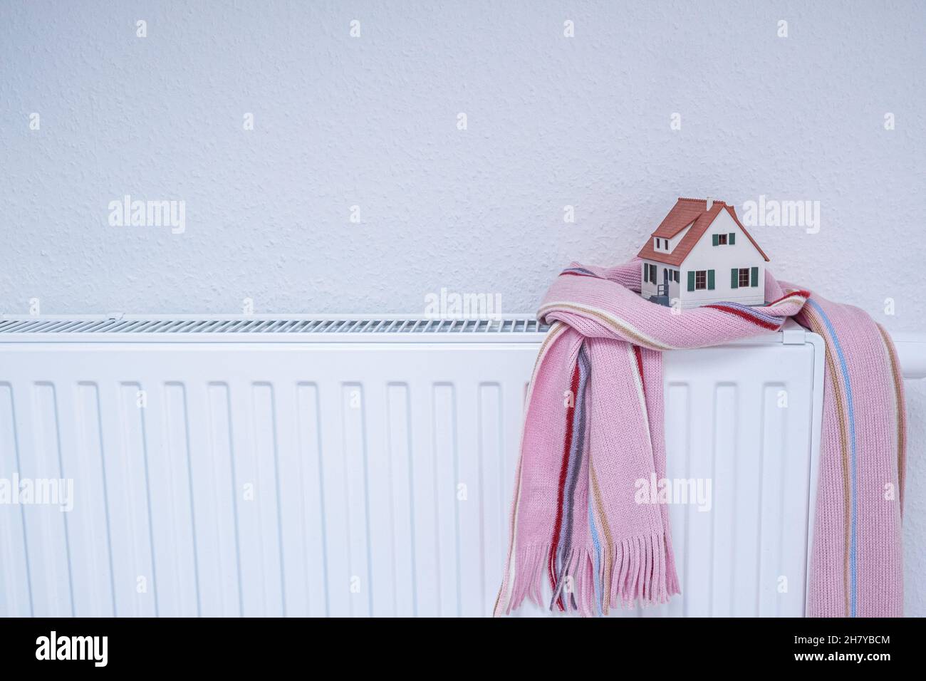 House-Modell in Schal auf Heizkörper im Inneren gewickelt. Heizungssaison Preis Stockfoto