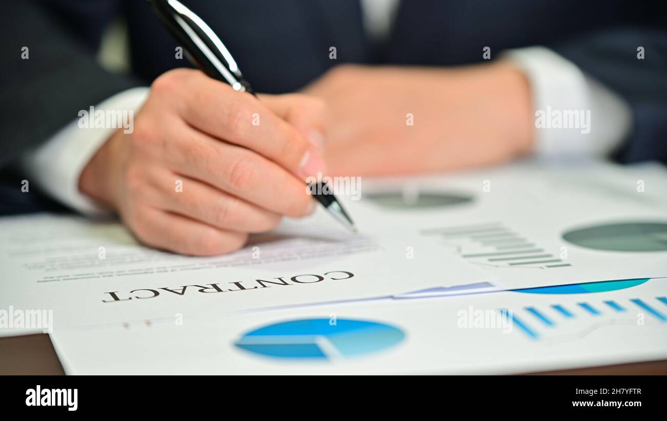 Geschäftsmann prüft Diagramme und Verträge auf dem Schreibtisch Stockfoto