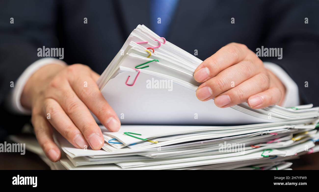 Die Hand eines Geschäftsmannes, der ein Papierbündel hält Stockfoto