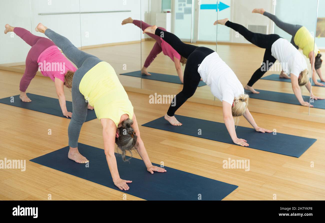 Gruppe reifer Frauen, die Yoga-Meditation in ardha chandrasana-Pose machen Stockfoto