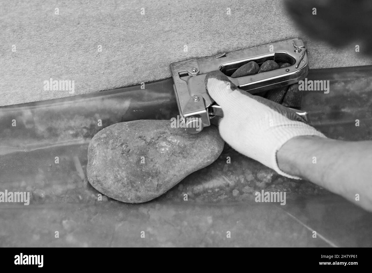 Der Mann klebt das Dämpfungsband auf den Mauerboden, den Schutz für den Bodenstelm, reparieren im Haus. Stockfoto