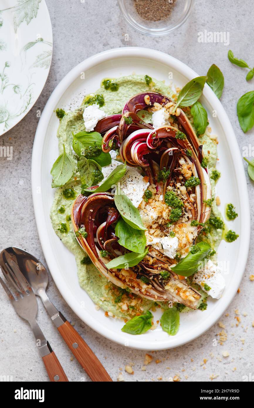 Gerösteter Radicchio-Salat mit Feta, grünem Tahini, Pinienkernen und Basilikum-Pesto. Radicchio rosso di treviso tardivo, italienischer roter Chicorée. Gesunde Mahlzeit reci Stockfoto