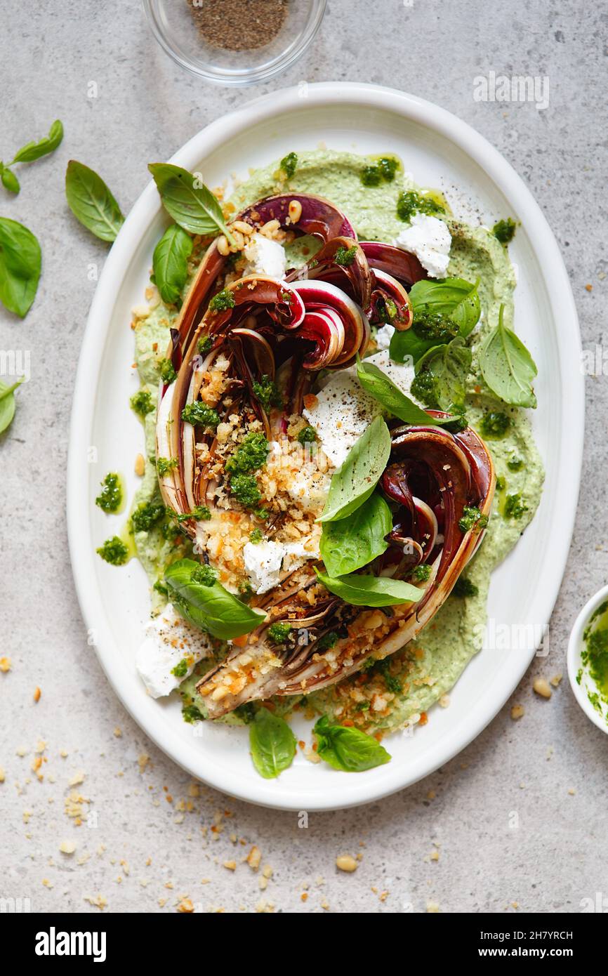 Gerösteter Radicchio-Salat mit Feta, grünem Tahini, Pinienkernen und Basilikum-Pesto. Radicchio rosso di treviso tardivo, italienischer roter Chicorée. Gesunde Mahlzeit reci Stockfoto