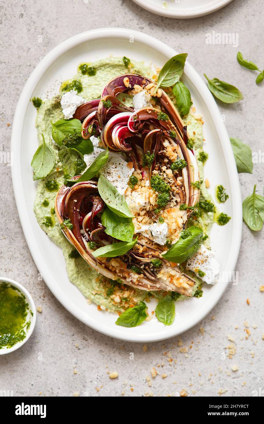 Gerösteter Radicchio-Salat mit Feta, grünem Tahini, Pinienkernen und Basilikum-Pesto. Radicchio rosso di treviso tardivo, italienischer roter Chicorée. Gesunde Mahlzeit reci Stockfoto