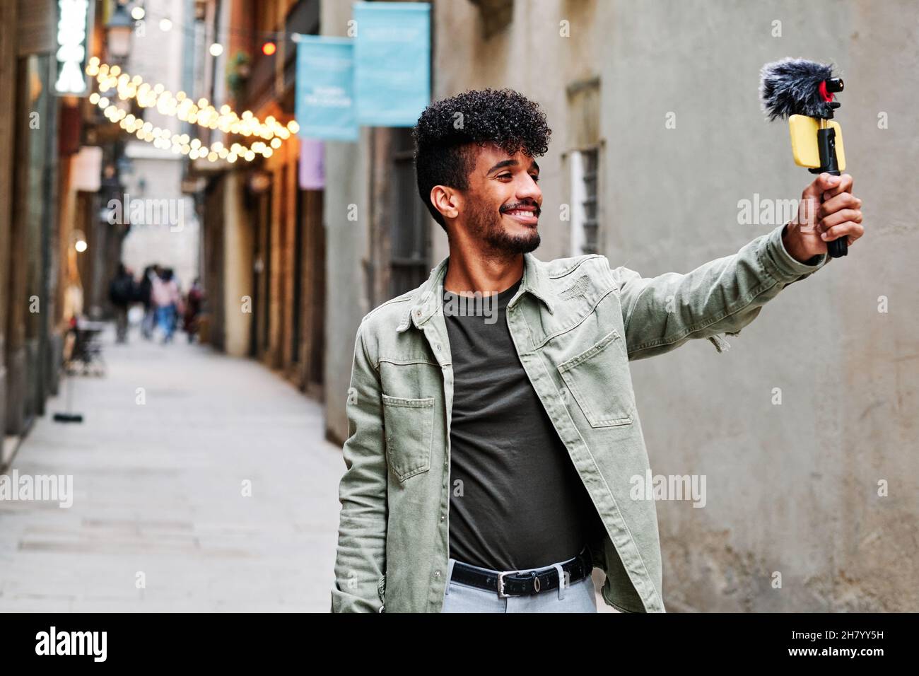 Junger Mann, der mit seinem Mobiltelefon und einem Mikrofon im Freien streamt Stockfoto