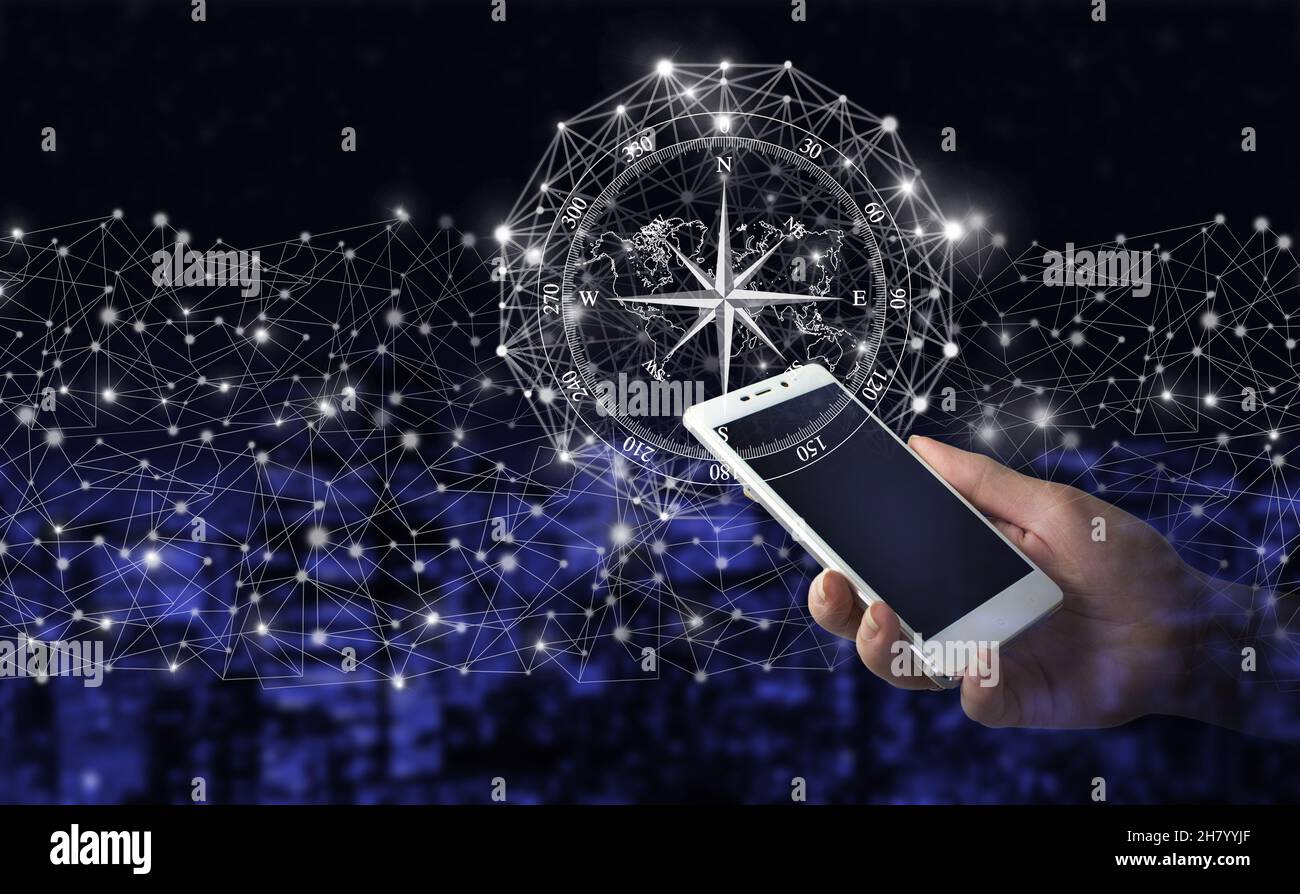 Navigationskonzept. Map und Innovationskonzept. Handgriff weißes Smartphone mit digitalem Hologramm Kompass Zeichen auf Stadt dunkel verschwommen Hintergrund. Global Stockfoto