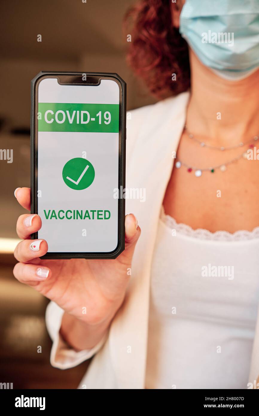 Nicht erkennbare Frau, die eine Covid-19-Impfzertifizierung auf dem Smartphone vorweisen kann Stockfoto