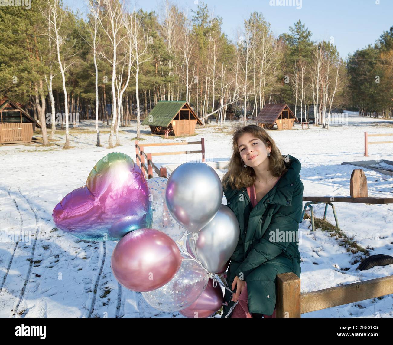 Porträt eines zarten niedlichen Teenager-Mädchen, Geburtstagskind, 16-17 Jahre alt, hält viele bunte Ballons in ihren Händen. Sonnigen Wintertag. Fühlt sich großartig, fe Stockfoto