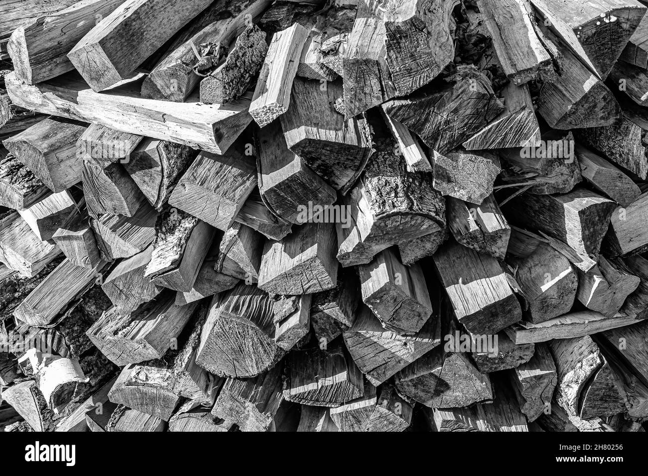 Schwarz-weißer Hintergrund des Haufenbrennholzstapels aus natürlichem Holz. Stockfoto