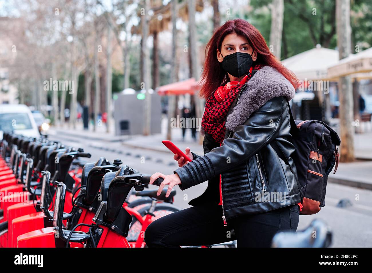 Frau mit Smartphone in einer Fahrradverleihstation. Stockfoto