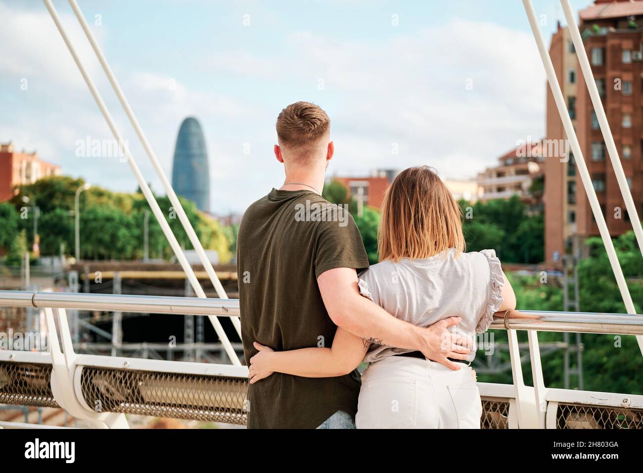 Glückliches junges Paar, ein gutaussehender Mann und ein kurvengelagertes Modell, in einer Brücke mit Blick auf die Skyline von Barcelona Stockfoto