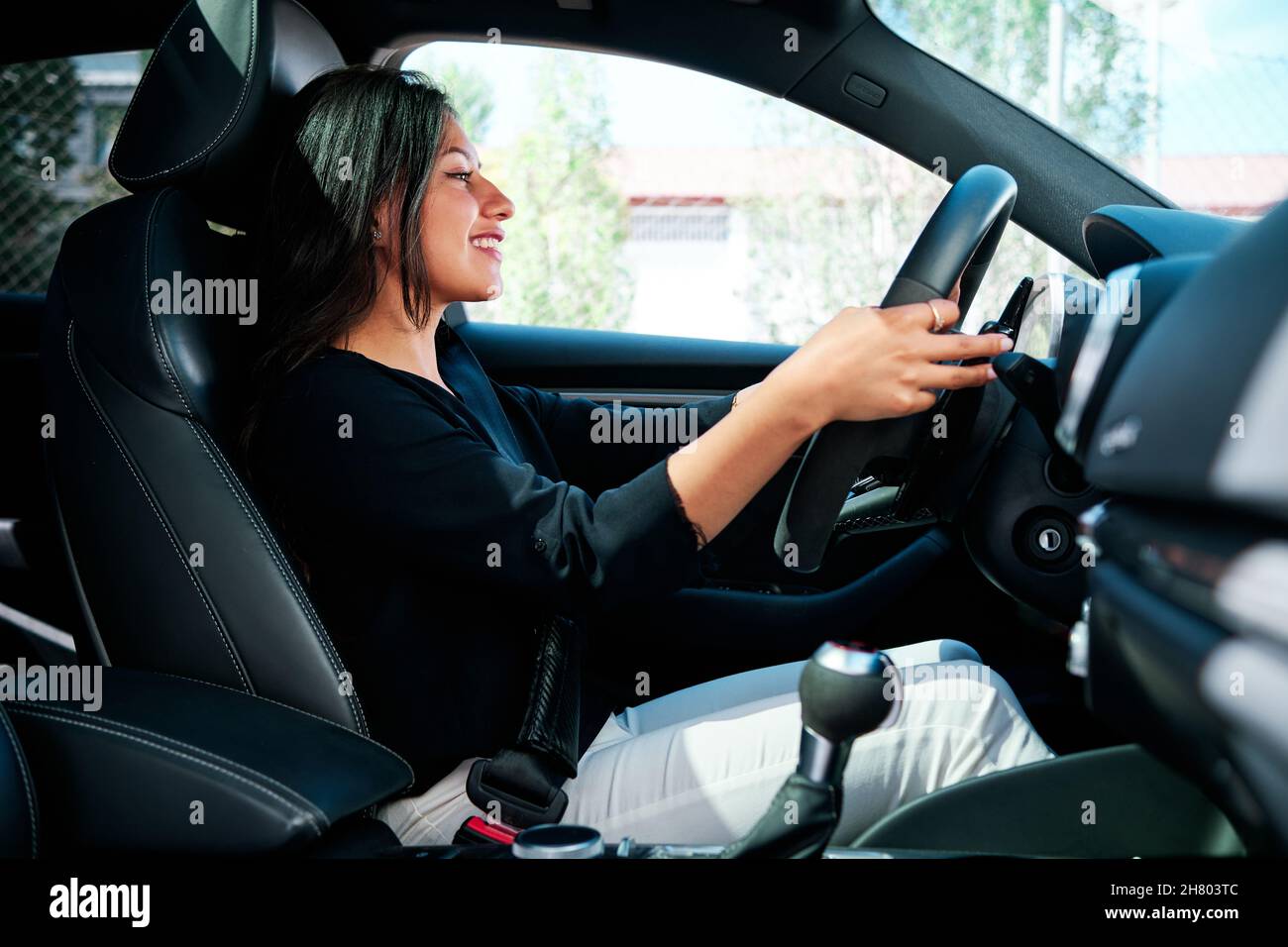Junge lateinische Frau, die ein Luxusauto fährt Stockfoto