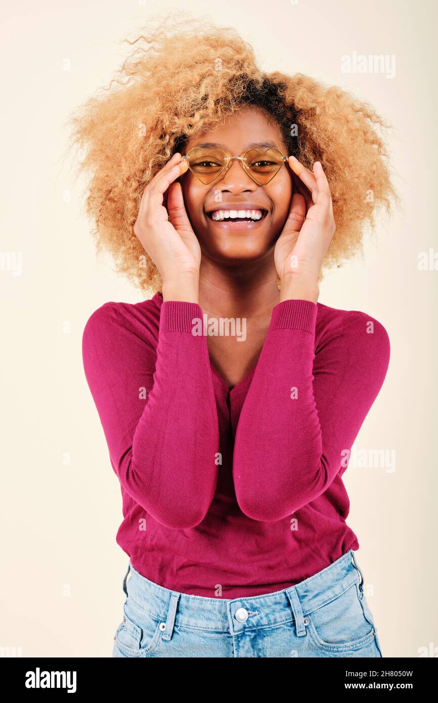 Junge Afro-Frau mit Sonnenbrille und lächelnd, während sie über einem isolierten Hintergrund steht. Stockfoto