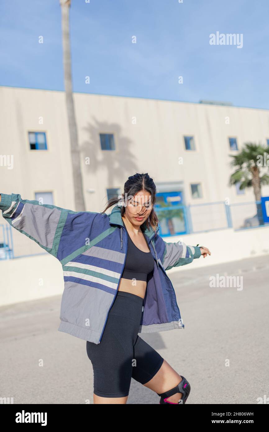 Ganzer Körper der aktiven schnellen Frau in lässiger Kleidung Reiten Skateboard auf Sportplatz in der Nähe von hohen Bäumen am Sommertag Stockfoto