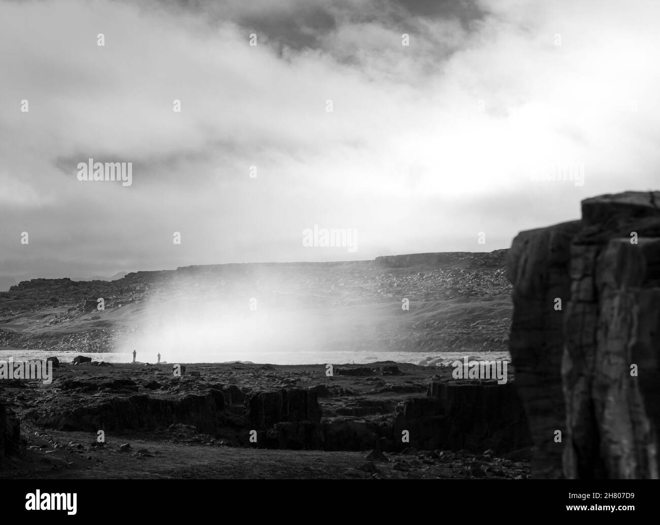 Schwarz und weiß von See in der Nähe der Küste mit Felsbrocken umgeben von Hügeln gegen bewölkten Himmel bei nebligen Wetter in der wilden Natur Stockfoto