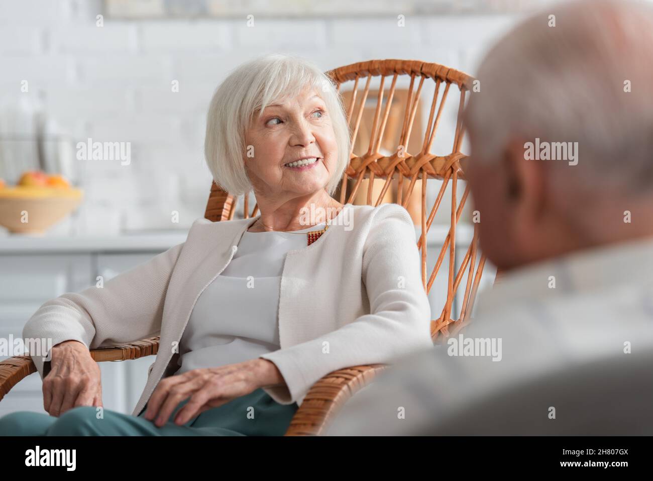 Ältere Frau, die im Pflegeheim in der Nähe einer verschwommenen Freundin wegschaut Stockfoto