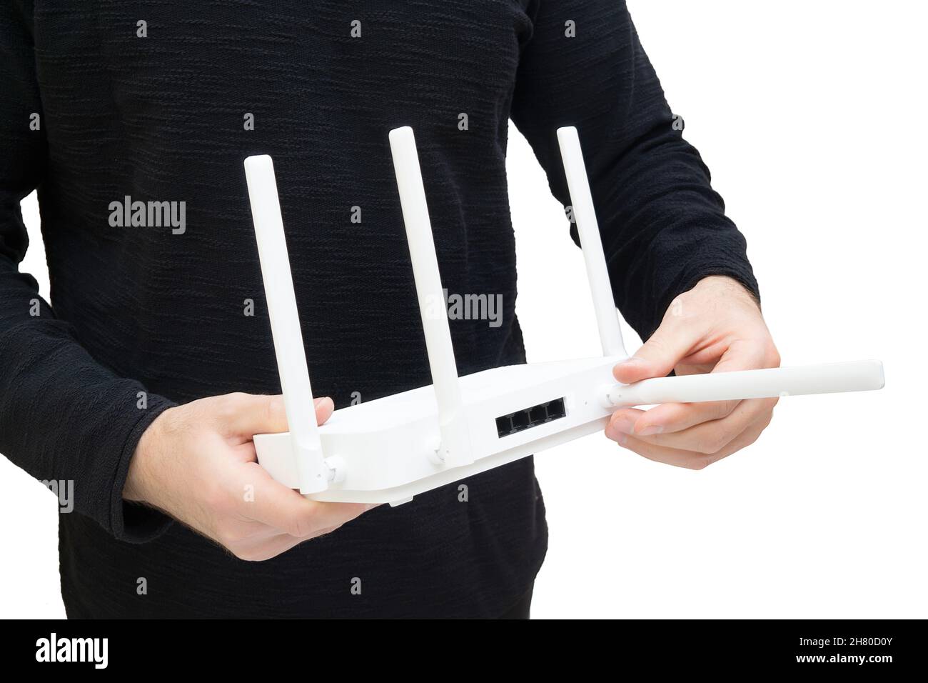 Mann, der einen modernen Dualband wi-Fi 6 Router hält und auf eine der Antennen zeigt. Bessere Abdeckung und bessere Signalübertragung durch optimale Positionierung. Stockfoto