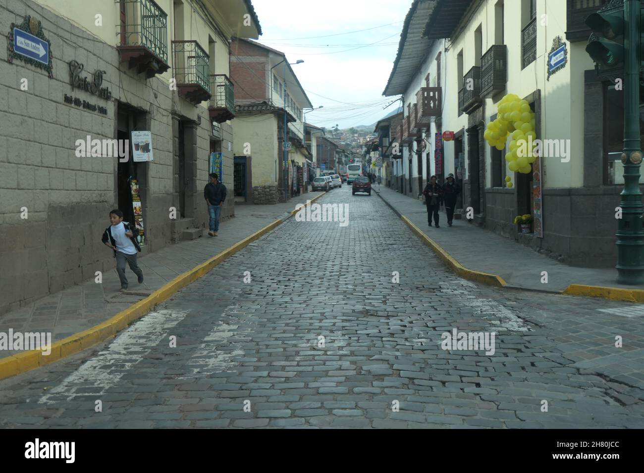 Cuzco Peru Stadtzentrum Ballons gelbe Straße Kopfsteinpflaster Straße Balkons alter Stil Südamerika Leute gehen durch die Einheimischen Dorf Stockfoto