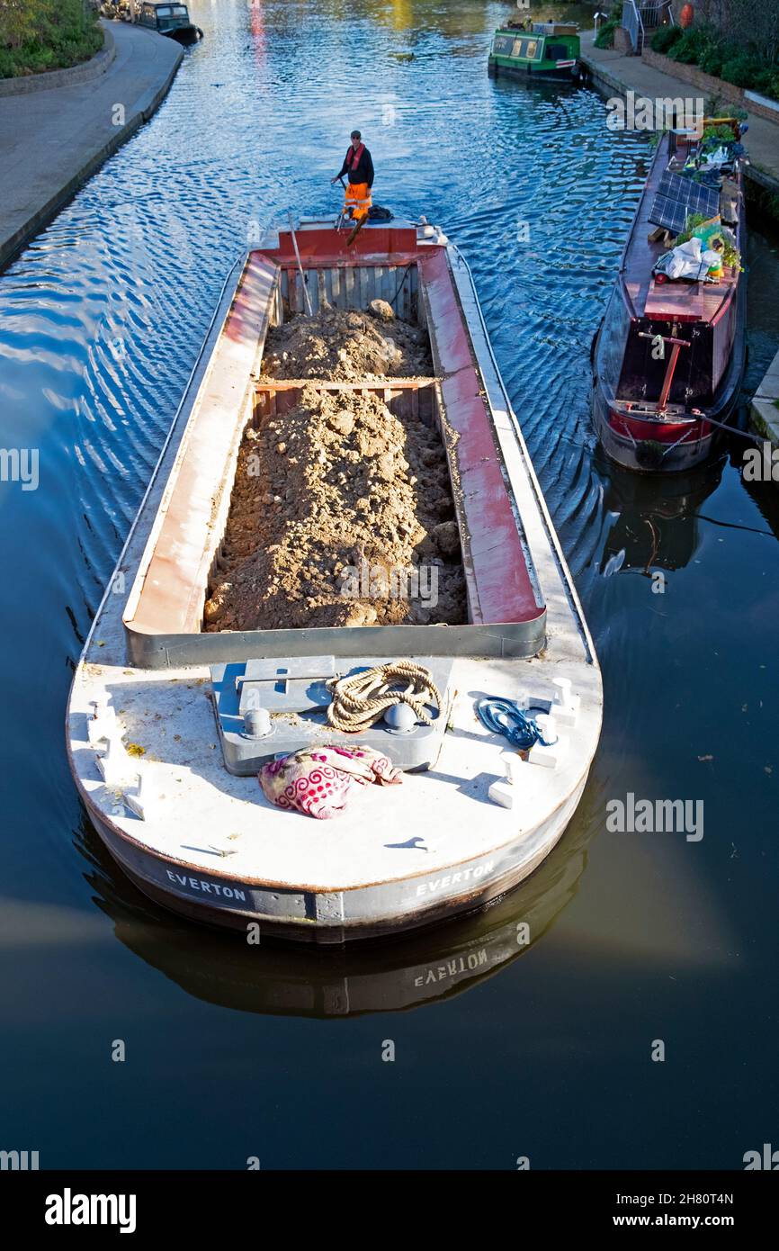 Mann fährt Barge mit Lastschutt auf dem Regents Canal Vertikale Ansicht von der Brücke am Kings Cross Granary Square in London N1C England Großbritannien KATHY DEWITT Stockfoto
