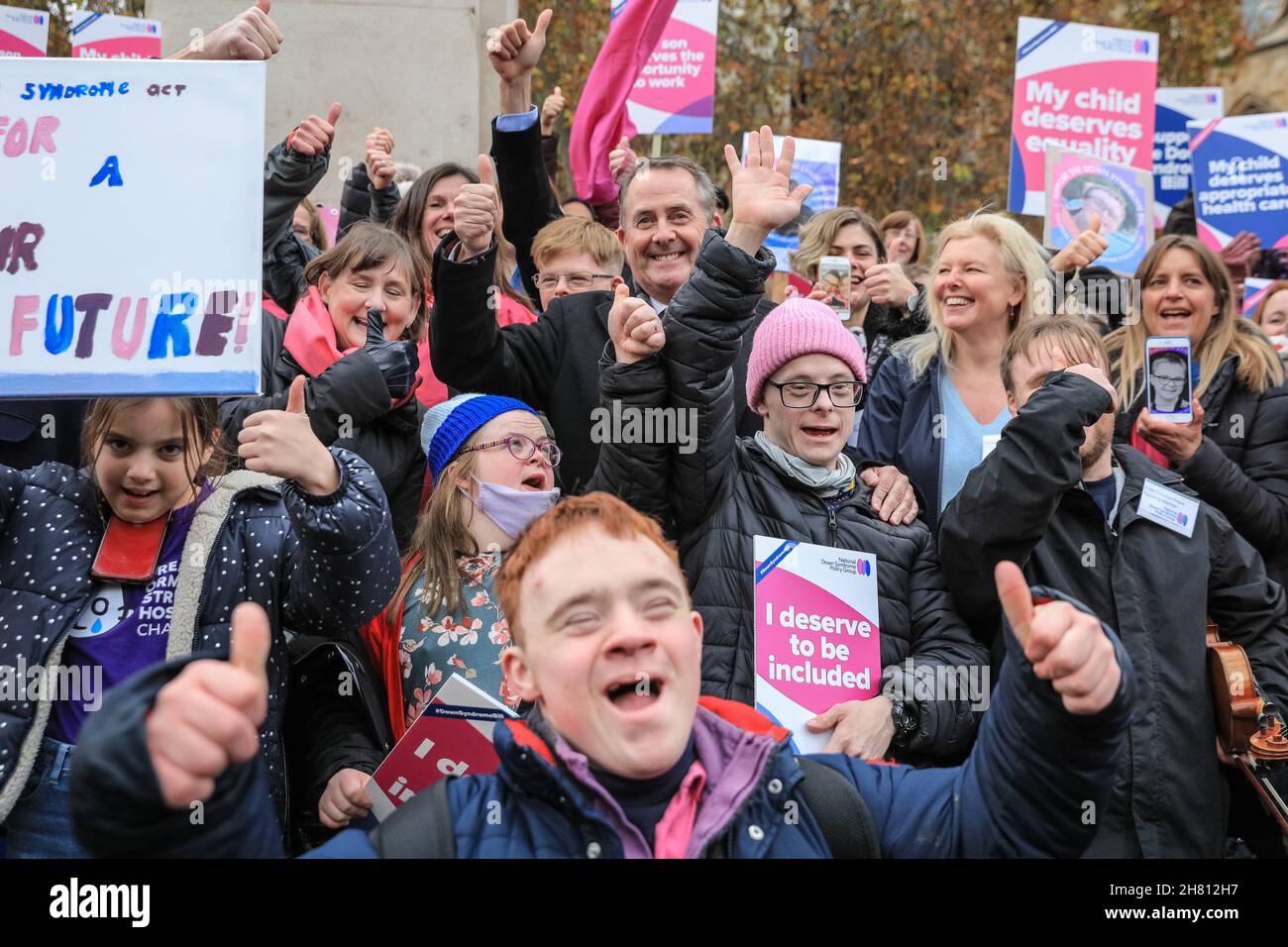 Westminster, London, Großbritannien, 26th. November 2021. Dr. Liam Fox, ehemaliger Staatssekretär für Verteidigung, feiert gemeinsam mit Aktivisten der National Down Syndrom Policy Group die erste Hürde im Parlament. Aktivisten außerhalb des Parlaments unterstützen den von Liam Fox eingeführten Down-Syndrom-Gesetzentwurf, der heute im Parlament seine Lesung aus dem Jahr 2nd hat und heute, nachdem die Regierung ihre Unterstützung für die Gesetzesüberstellung angekündigt hatte, diese Hürde beseitigen sollte. Der Gesetzentwurf soll neue Leitlinien für öffentliche Einrichtungen festlegen, um die Bedürfnisse von Menschen mit Down-Syndrom besser zu erfüllen. Stockfoto