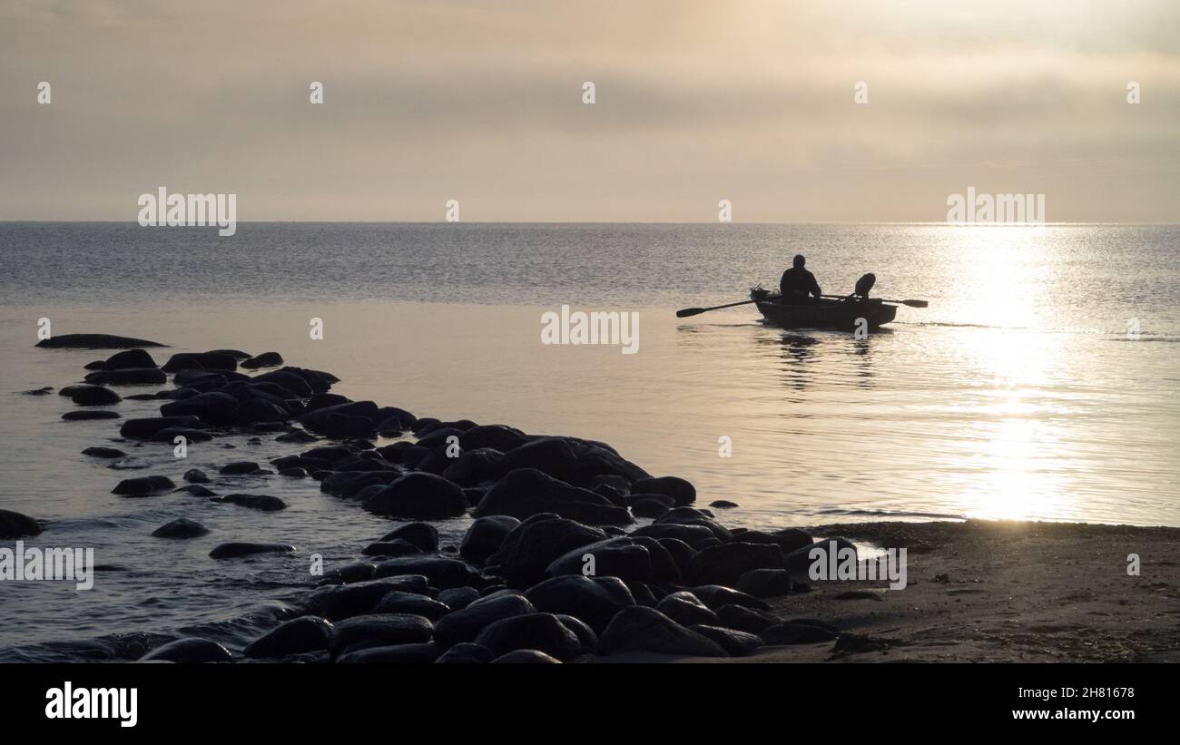 Ein Ruderboot auf dem Weg ins Meer steht im Kontrast zur Sonne Stockfoto