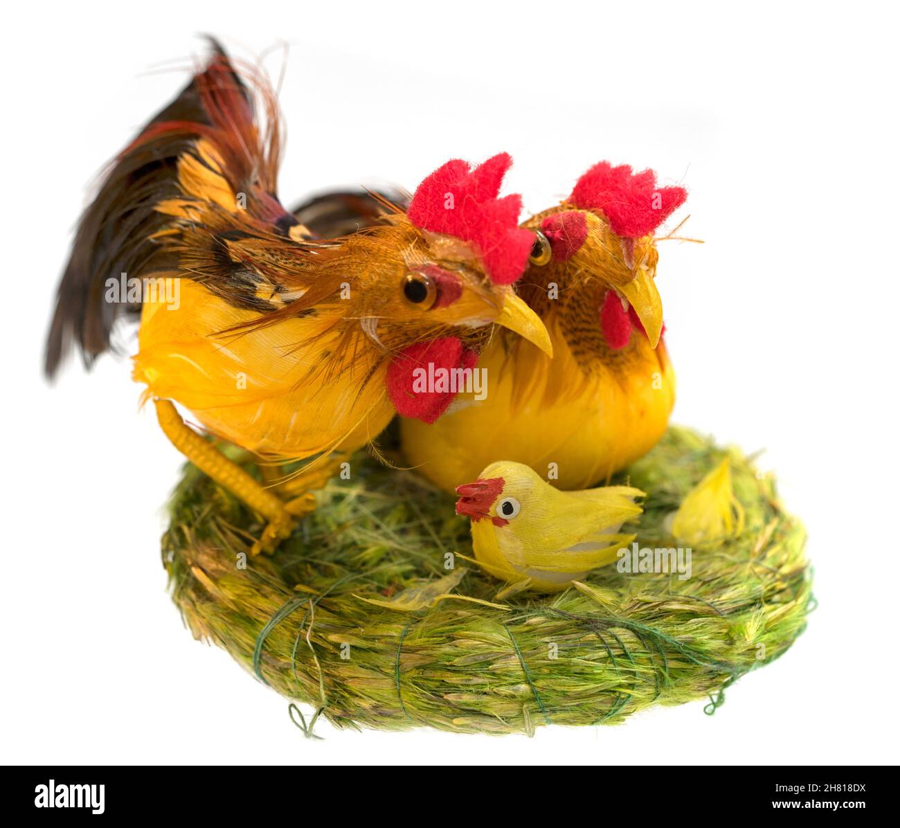 Hahn, Henne und Küken in einem Grasnest - Osterspielzeug isoliert auf weißem Hintergrund. Stockfoto