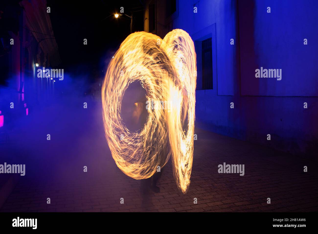 Feuershow mit spiralförmigen Formen in einem Bereich unter blauem Licht Stockfoto