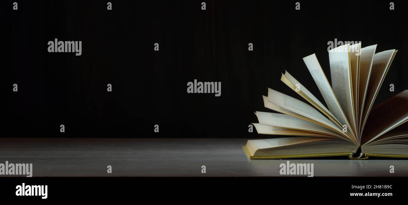 Offenes Buch, Hardback-Buch auf Holztisch auf dunklem Hintergrund. Zurück zur Schule, Bildung, Lesen. Speicherplatz kopieren Stockfoto