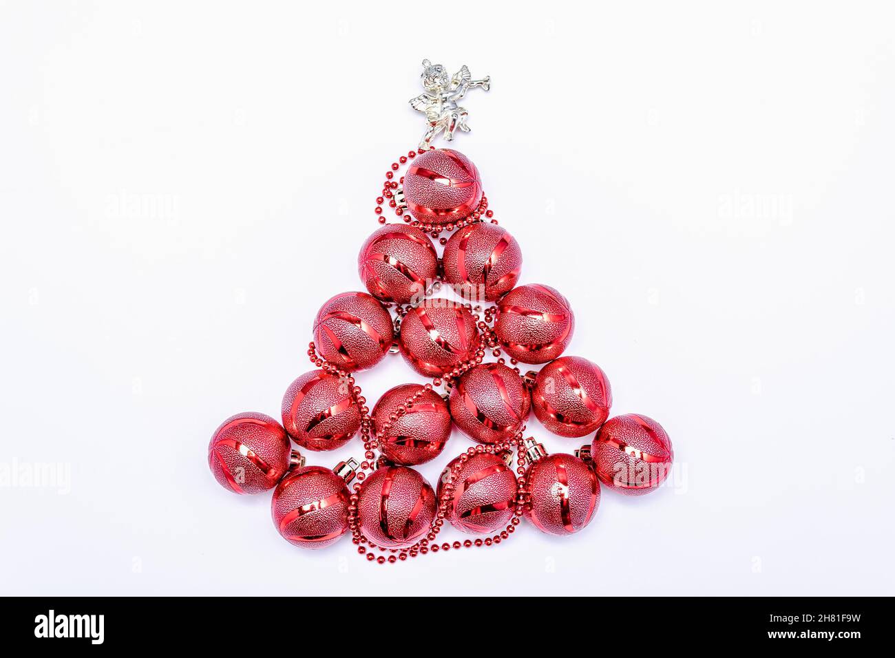 Weihnachtsbaum mit roten Weihnachtskugeln mit einem Engel gesäumt. Festliche Postkarte. Horizontales Foto. Stockfoto