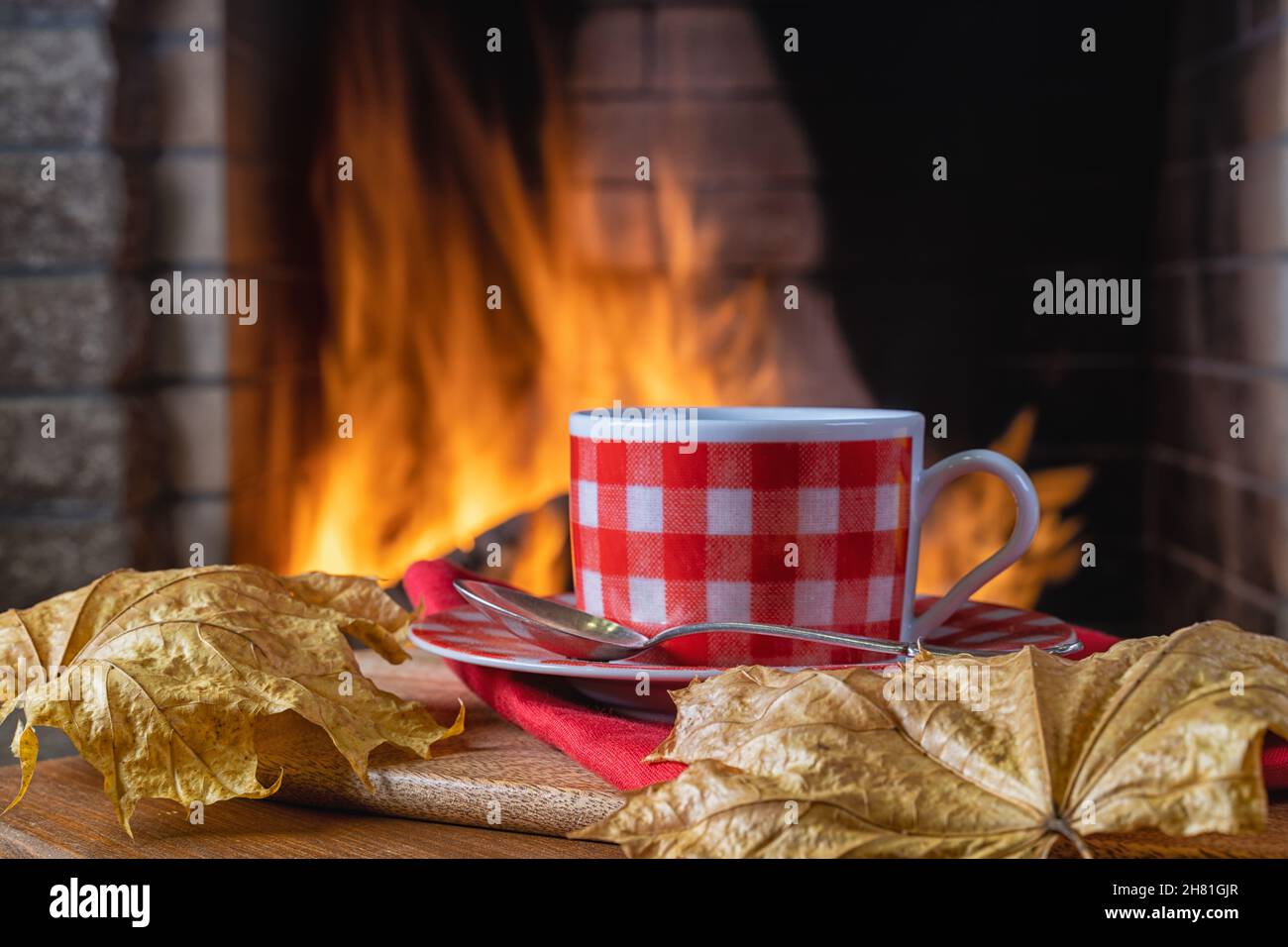 Tasse Tee oder Kaffee in der Nähe eines gemütlichen Kamins, in einem Landhaus, Herbst- oder Winterferien, horizontal. Stockfoto