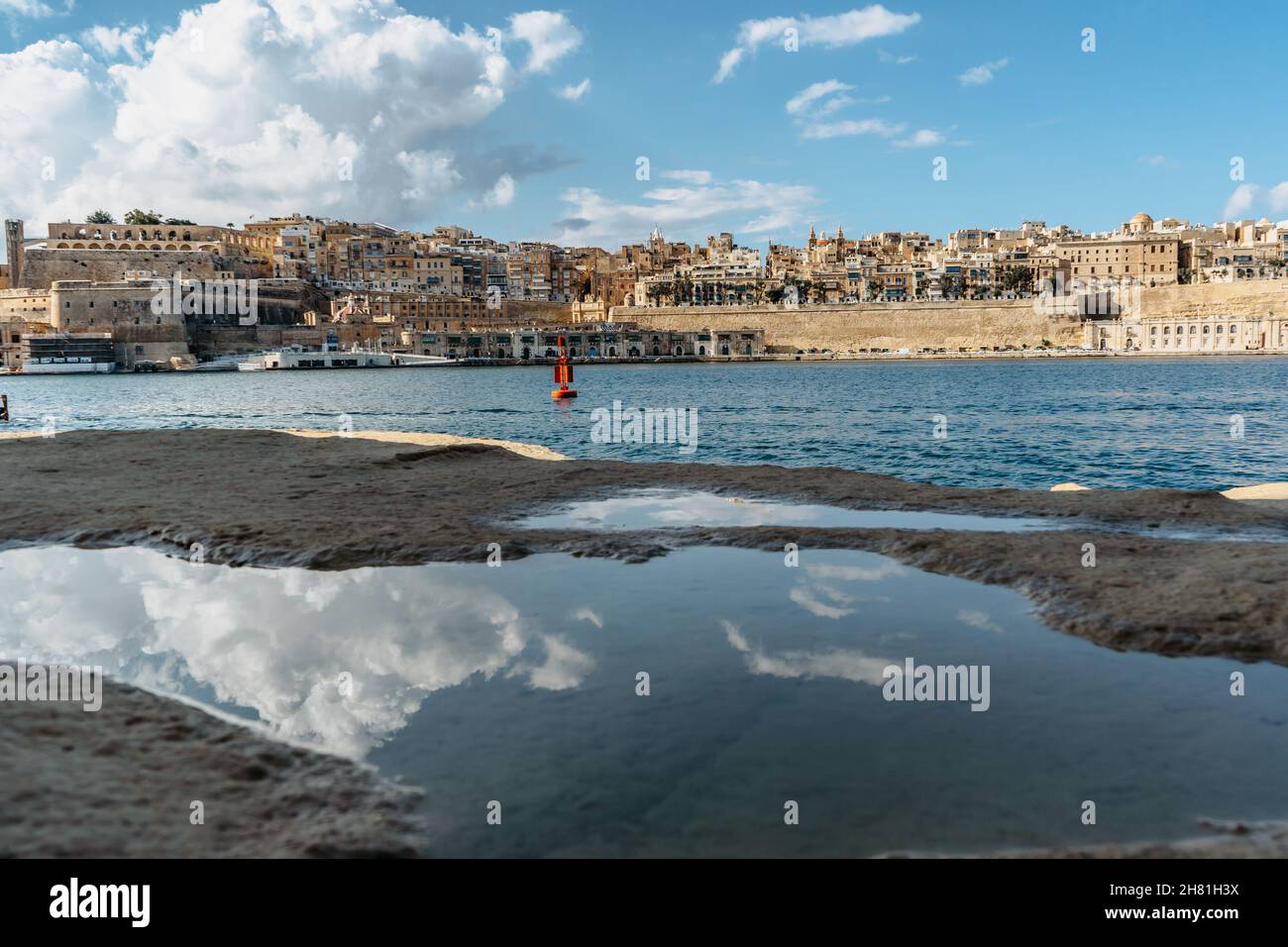 Panoramablick auf Valletta, Malta. Skyline der Stadt vom Hafen von Birgu Vittoriosa. Friedliche Stadtlandschaft, sonniger Sommertag, Wolken spiegeln sich im Wasser. Waterfront Stockfoto