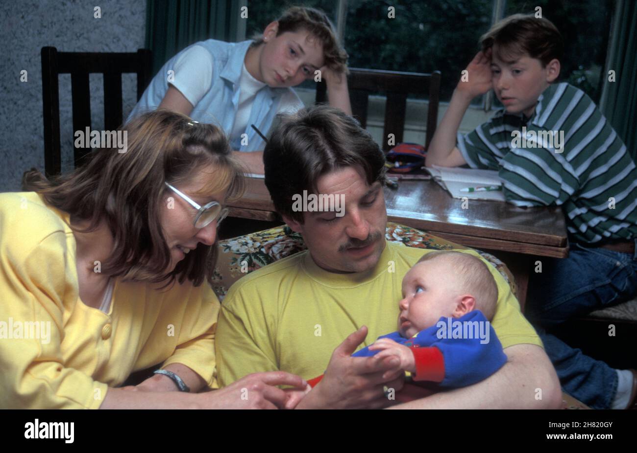 kaukasische Familie im sozialen Wohnungsbau mit neuem Baby und eifersüchtigen Geschwistern Stockfoto