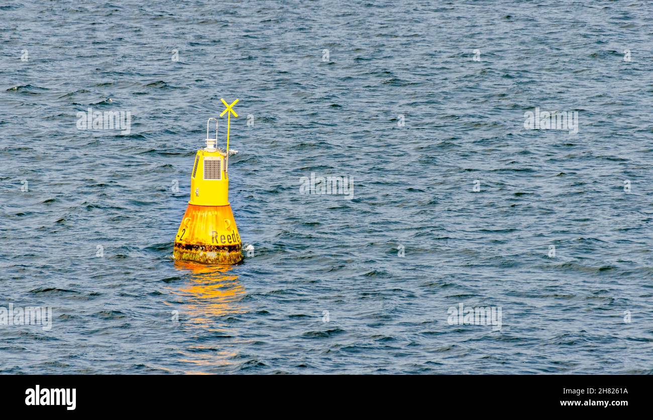Gelbes Navigationszeichen mit Sonnenkollektoren mit der Aufschrift „Reede (Roadstead)“ an der welligen Ostsee Stockfoto