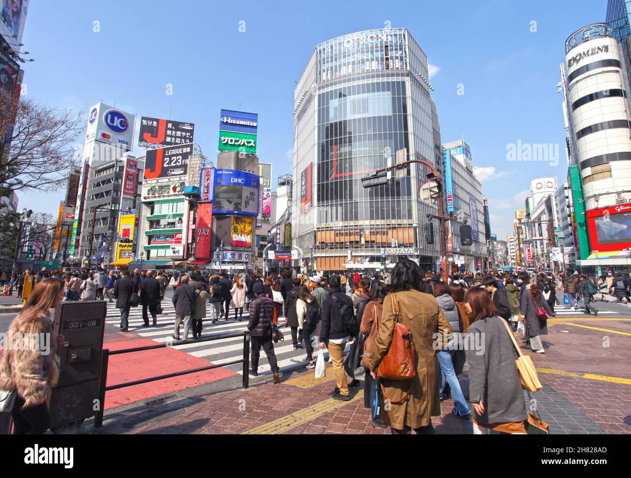 Shibuya Crossing auch bekannt als Shibuya Intersection und Shibuya Scramble in Tokio mit vielen Menschen, die die Kreuzung an einem sonnigen Tag überqueren. Stockfoto