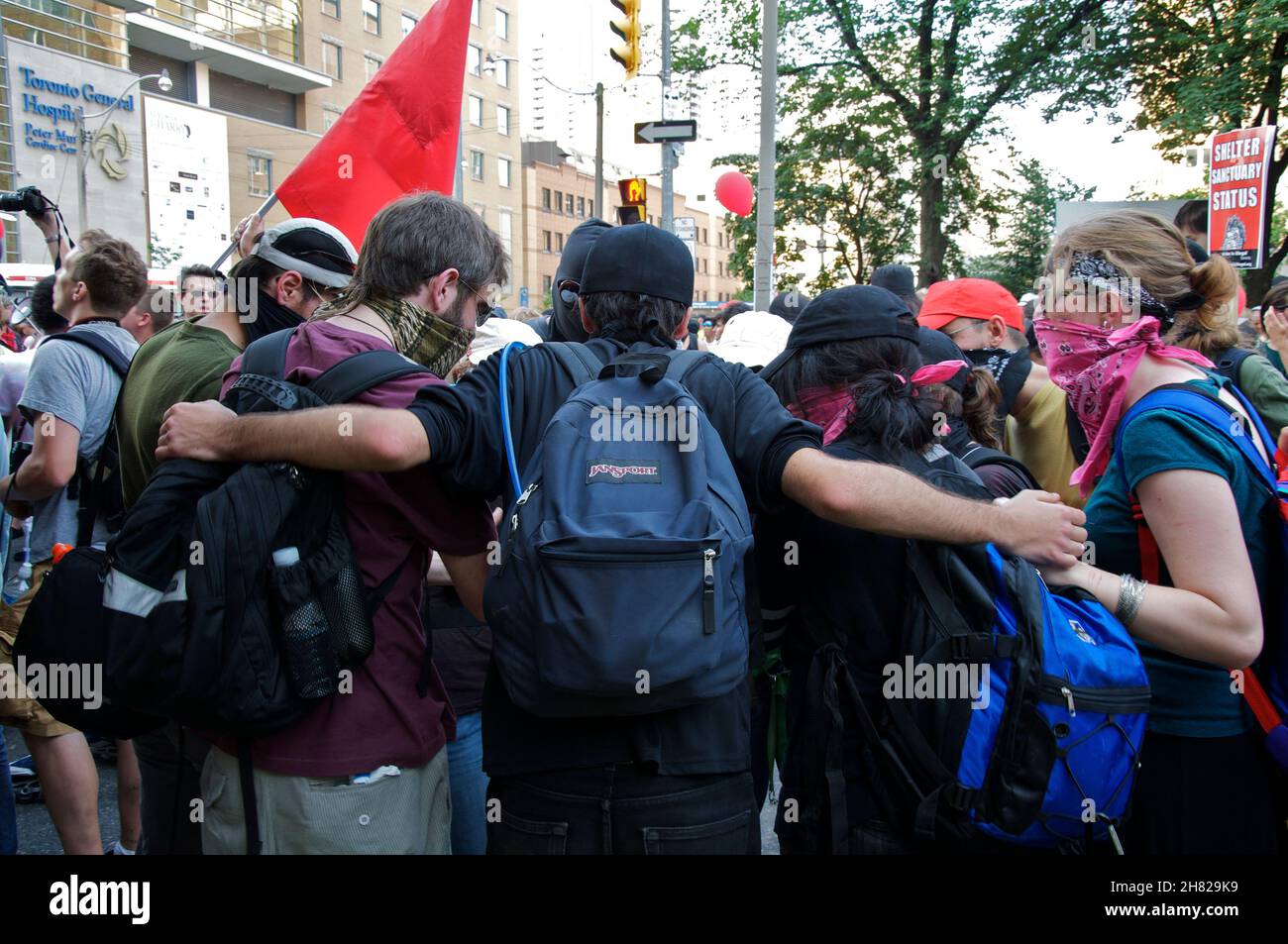 Toronto, Ontario, Kanada - 06/25/2010: Junge Menschen, die an einem Protest in der G-20 teilnehmen, während sie eine wiederverwendbare Gesichtsmaske tragen Stockfoto