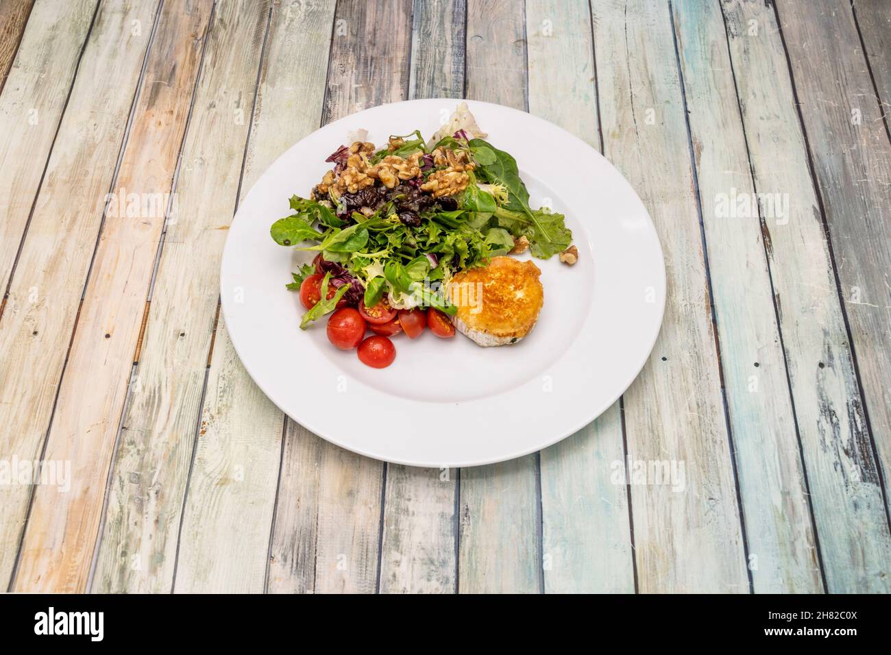 Salat mit Kirschtomaten, kalifornischen Walnüssen und Rosinen mit gebratenem Ziegenkäse Stockfoto