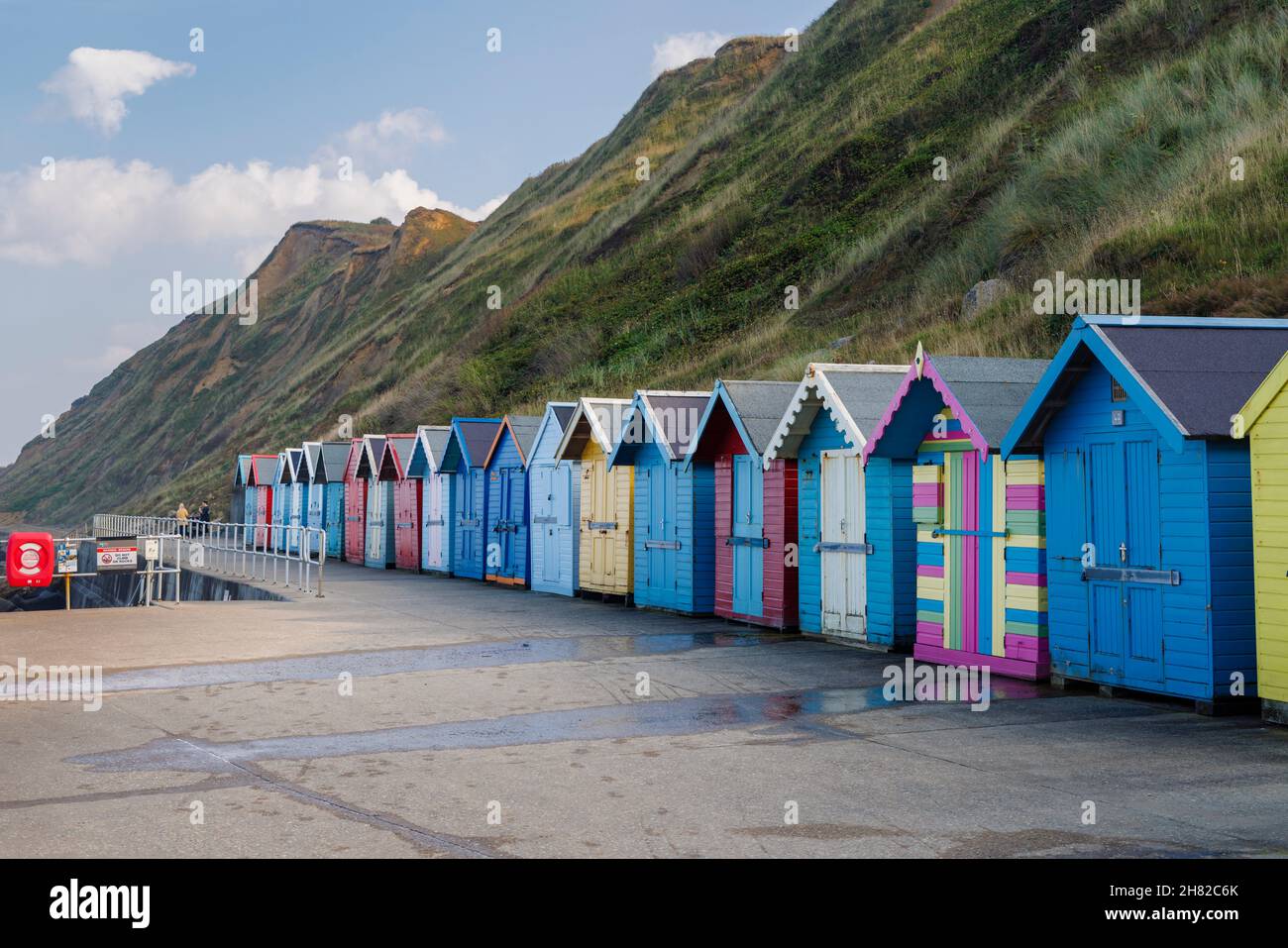 Eine Reihe von bunten Strandhütten an der Strandpromenade unterhalb der Klippen von Sheringham an der Nordküste von Norfolk, East Anglia, England Stockfoto