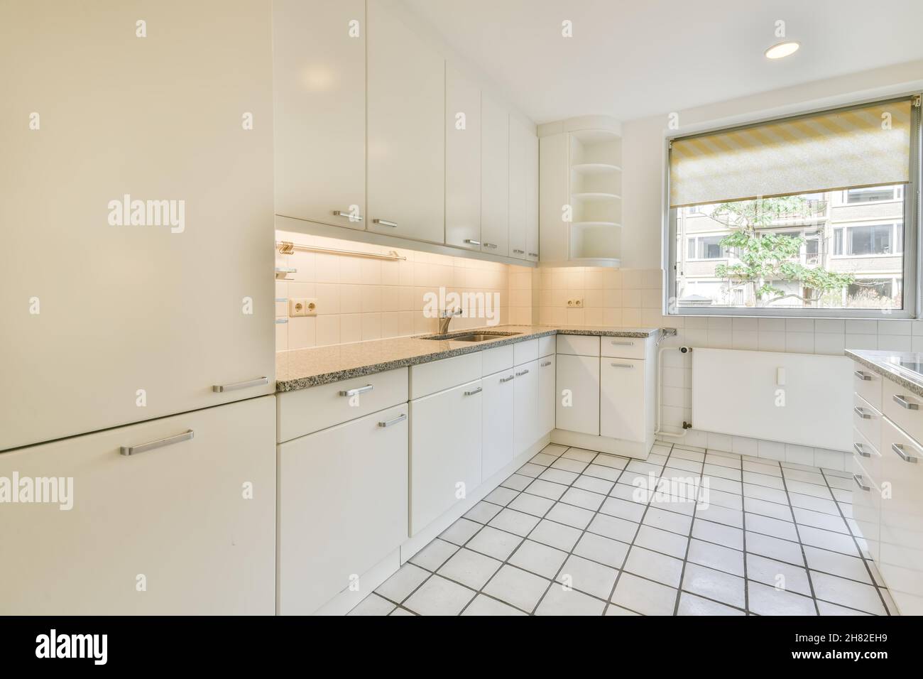 Weiß gefliester Boden in heller Küche mit Marmorarbeitspel Stockfoto