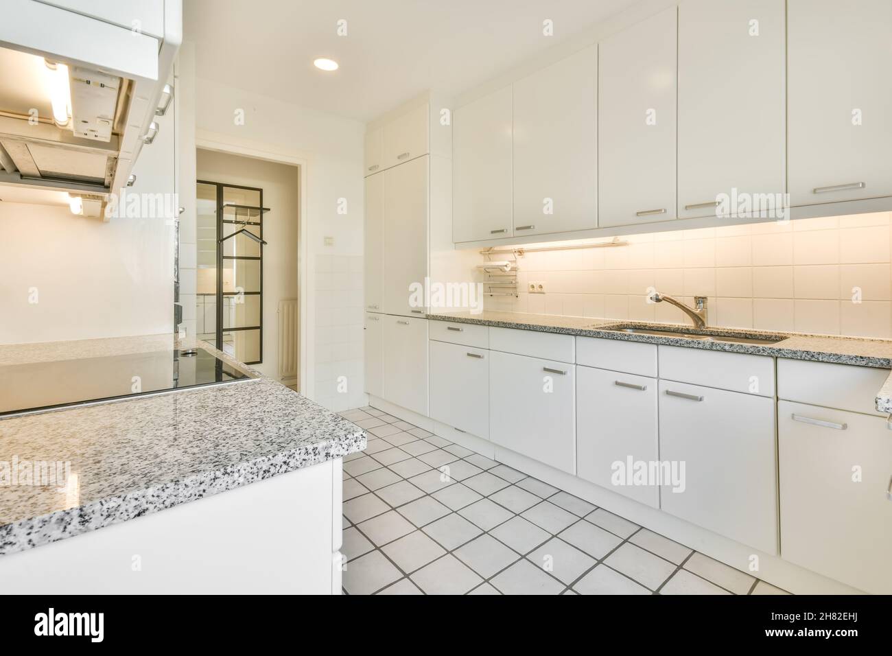 Weiß gefliester Boden in heller Küche mit Marmorarbeitspel Stockfoto