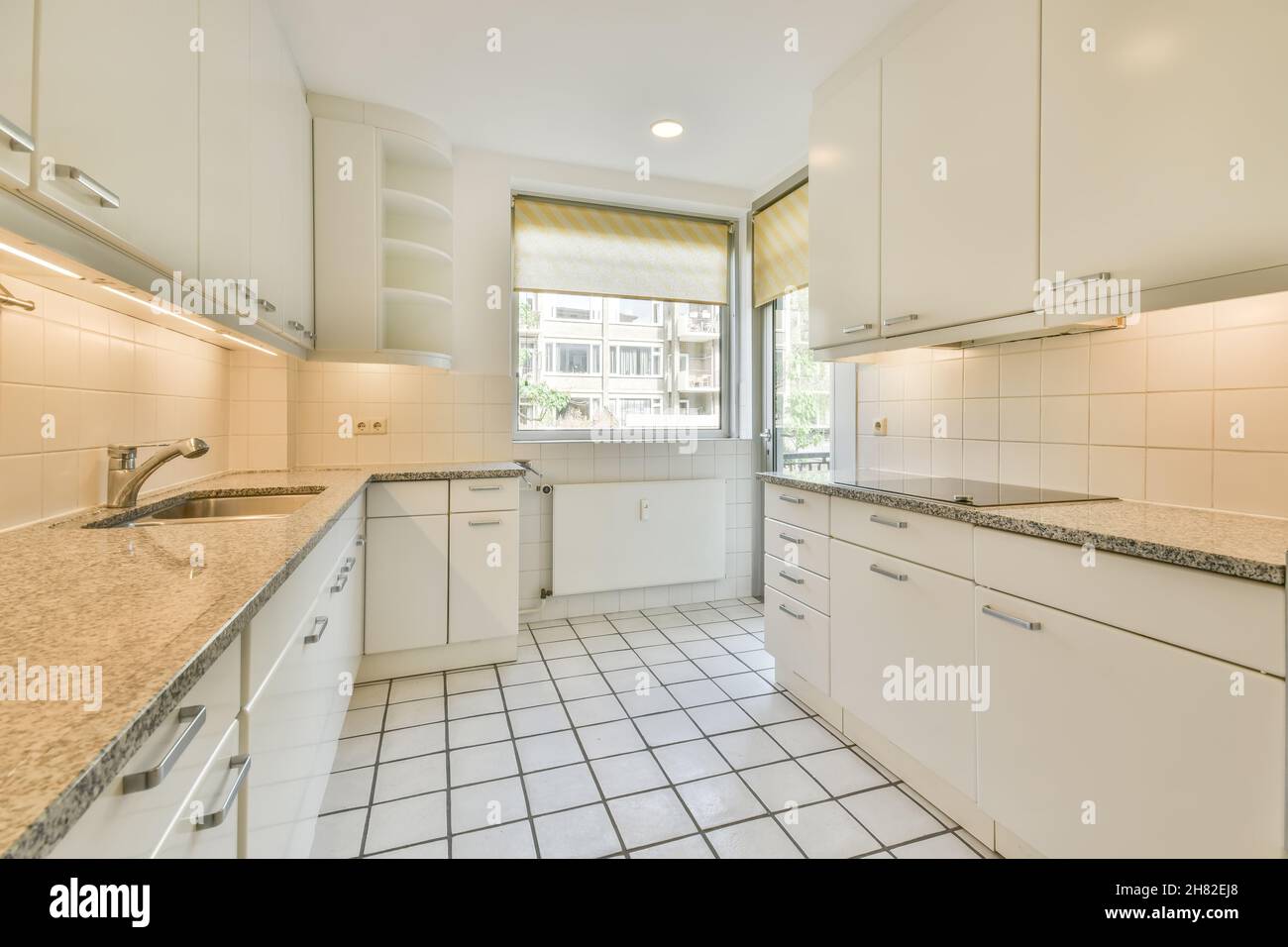 Weiß gefliester Boden in heller Küche mit Marmorarbeitspel Stockfoto