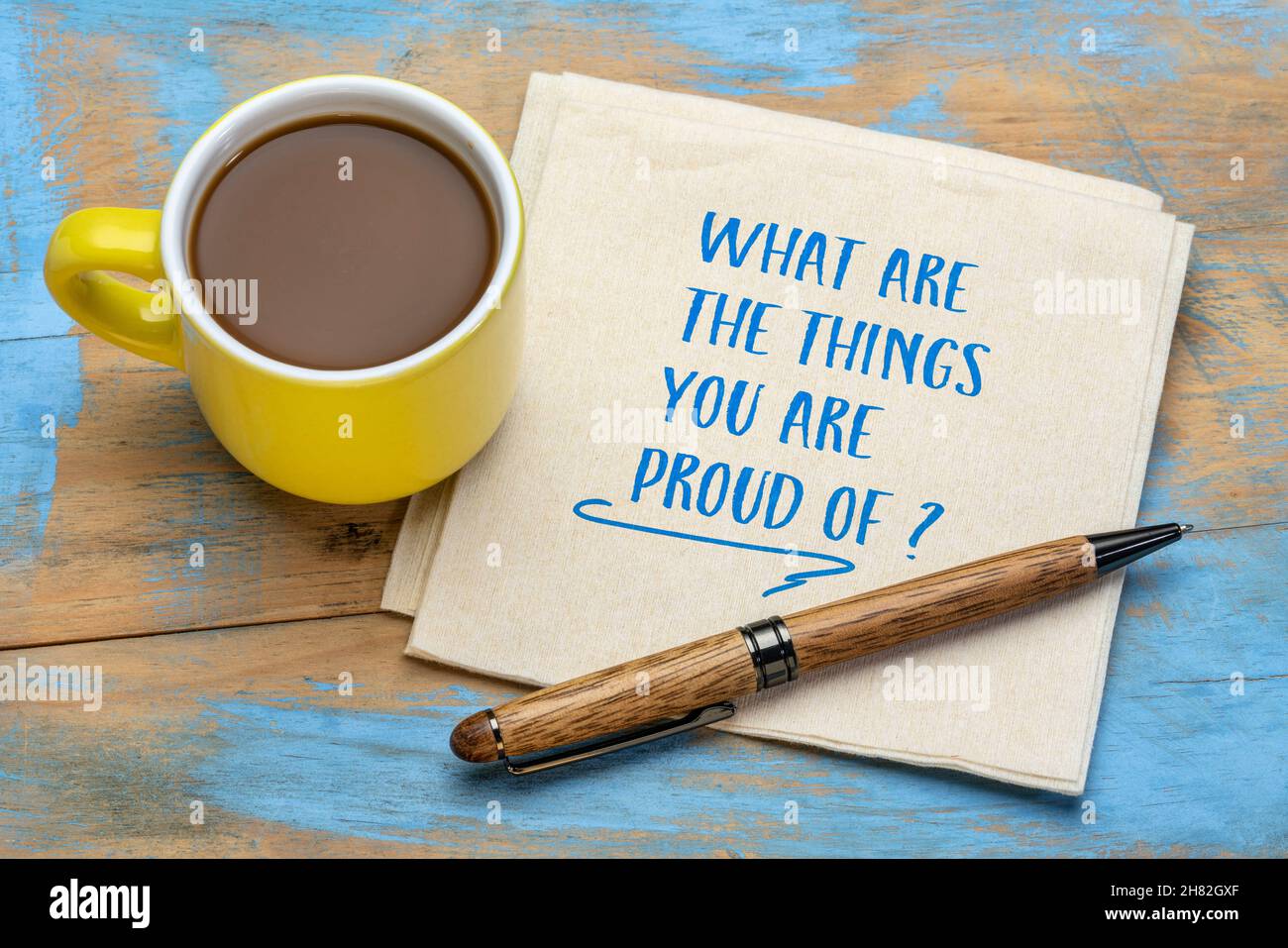 Worauf sind Sie stolz? Handschrift auf Serviette mit einer Tasse Kaffee. Überprüfen von Erfolgen und Erfolgen, persönliche Entwicklung Stockfoto