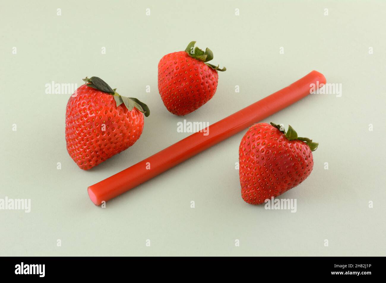Erdbeer-Lakritz-Stick mit frischen, rohen Erdbeeren auf hellgrünem Hintergrund Stockfoto
