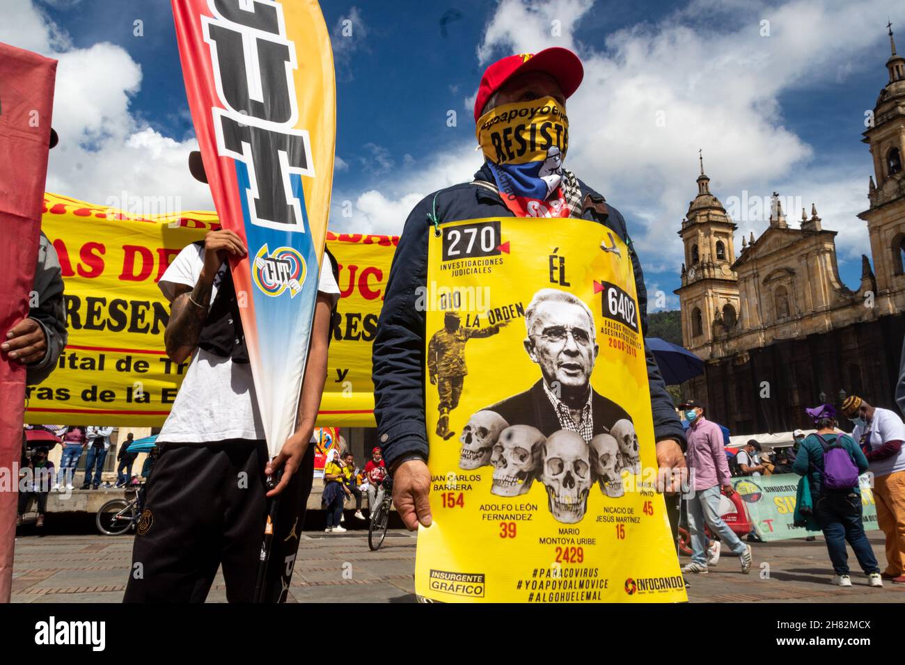 Ein Demonstranten hält ein Zeichen, das an die außergerichtlichen Tötungen von Kolumbien „Falsos Positivos“ erinnert, mit einem Foto des ehemaligen Präsidenten von Kolumbien und Senators Alvaro Uribe Velez während der Demonstrationen, die von Gewerkschaften gegen die Regierung von Präsident Ivan Duque Marquez am 25. November 2021 in Bogota, Kolumbien, aufgerufen wurden. Stockfoto