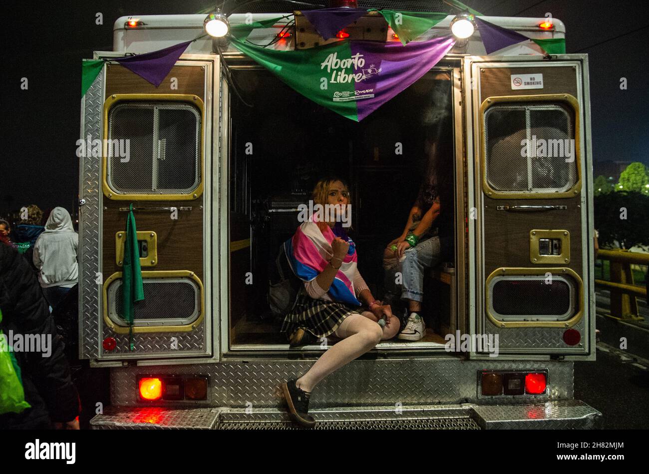 Eine Transgender-Frau posiert für ein Foto, während sie in einem Krankenwagen mit den Demonstranten während des Internationalen Tages zur Beseitigung der Gewalt gegen Frauen-Demonstrationen in Bogota, Kolumbien, am 25. November 2021 fährt. Stockfoto