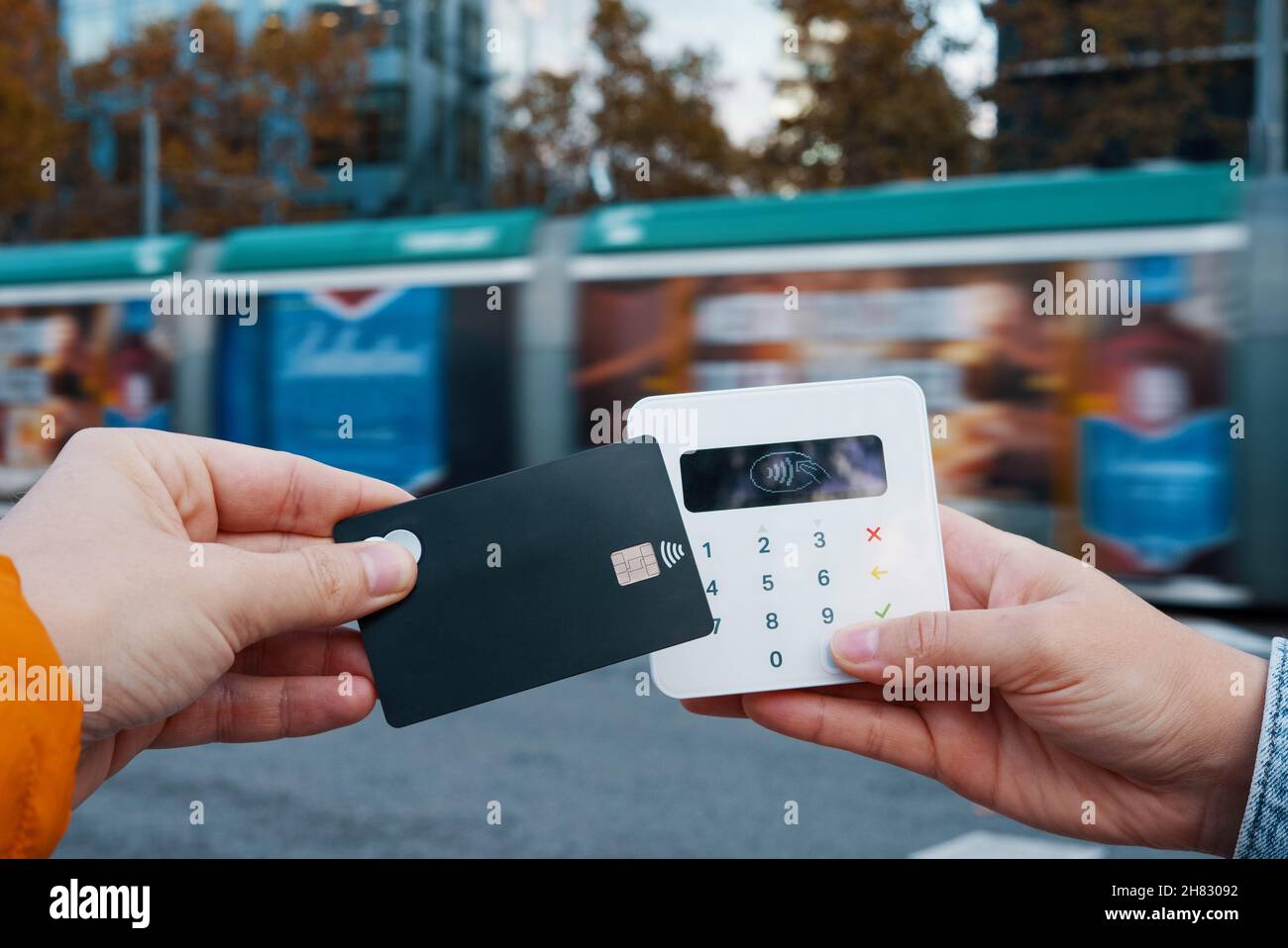 Männer ohne Gesicht und Plastikkarte, die NFC-Kauf am POS-Terminal für Busse in der Stadt machen Stockfoto