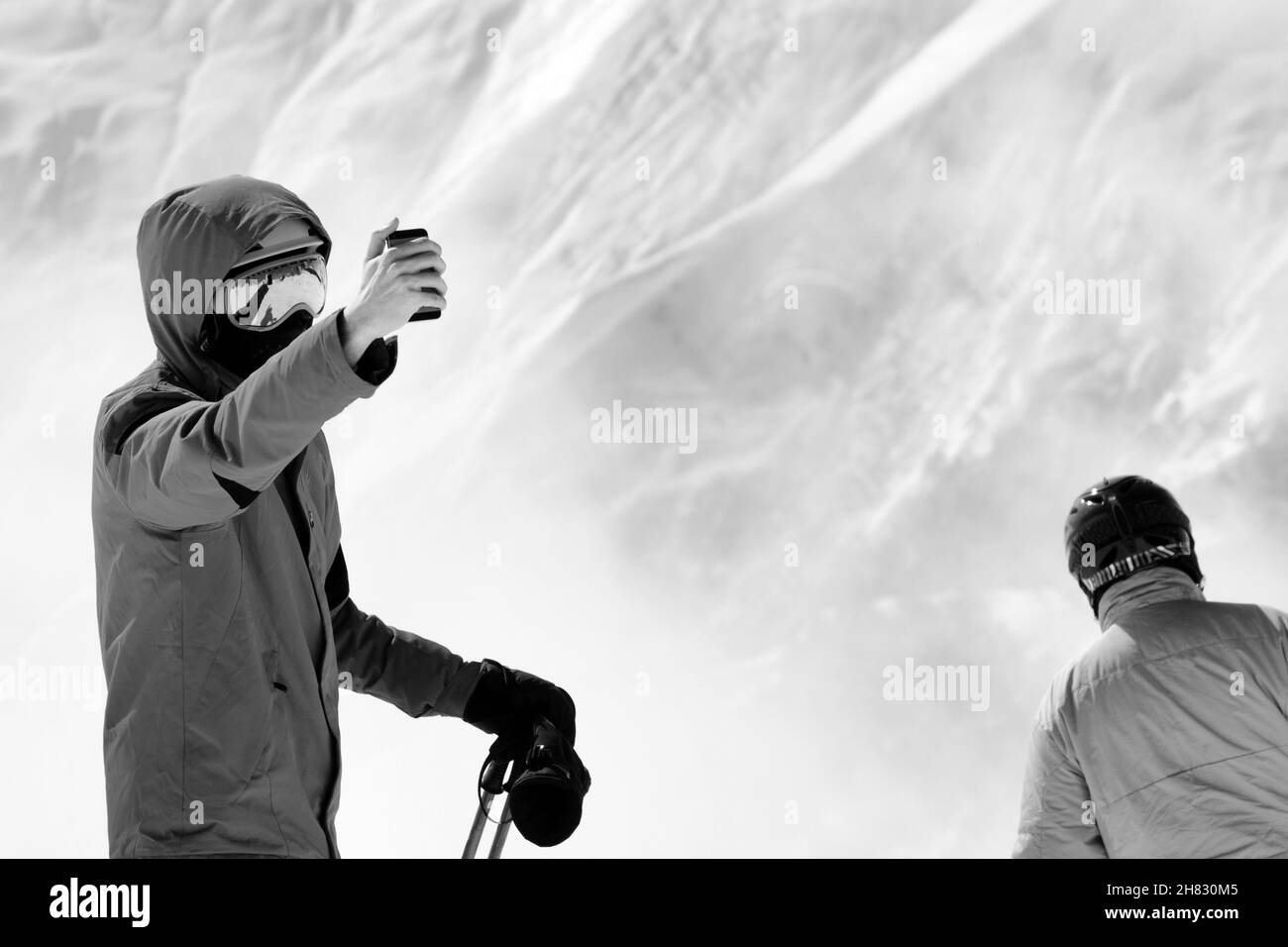 Skifahrer macht Selfie auf Kameratelefon und Schneeberge im Nebel im Hintergrund. Kaukasus im Winter, Georgien, Region Gudauri. Schwarze und weiße Tonne Stockfoto