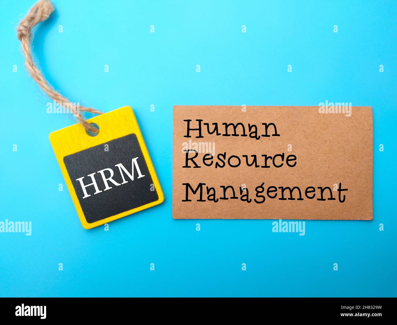 Farbiger Holzbaord und braune Karte mit Text HRM (Human Resource Management) geschrieben Stockfoto
