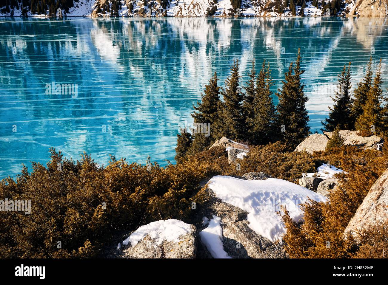 Schöne Landschaft von Bergsee mit blauem Eis und Fichtenwald im Winter Stockfoto