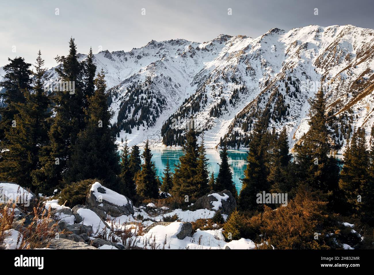 Schöne Landschaft von Bergsee mit blauem Eis und Fichtenwald im Winter Stockfoto